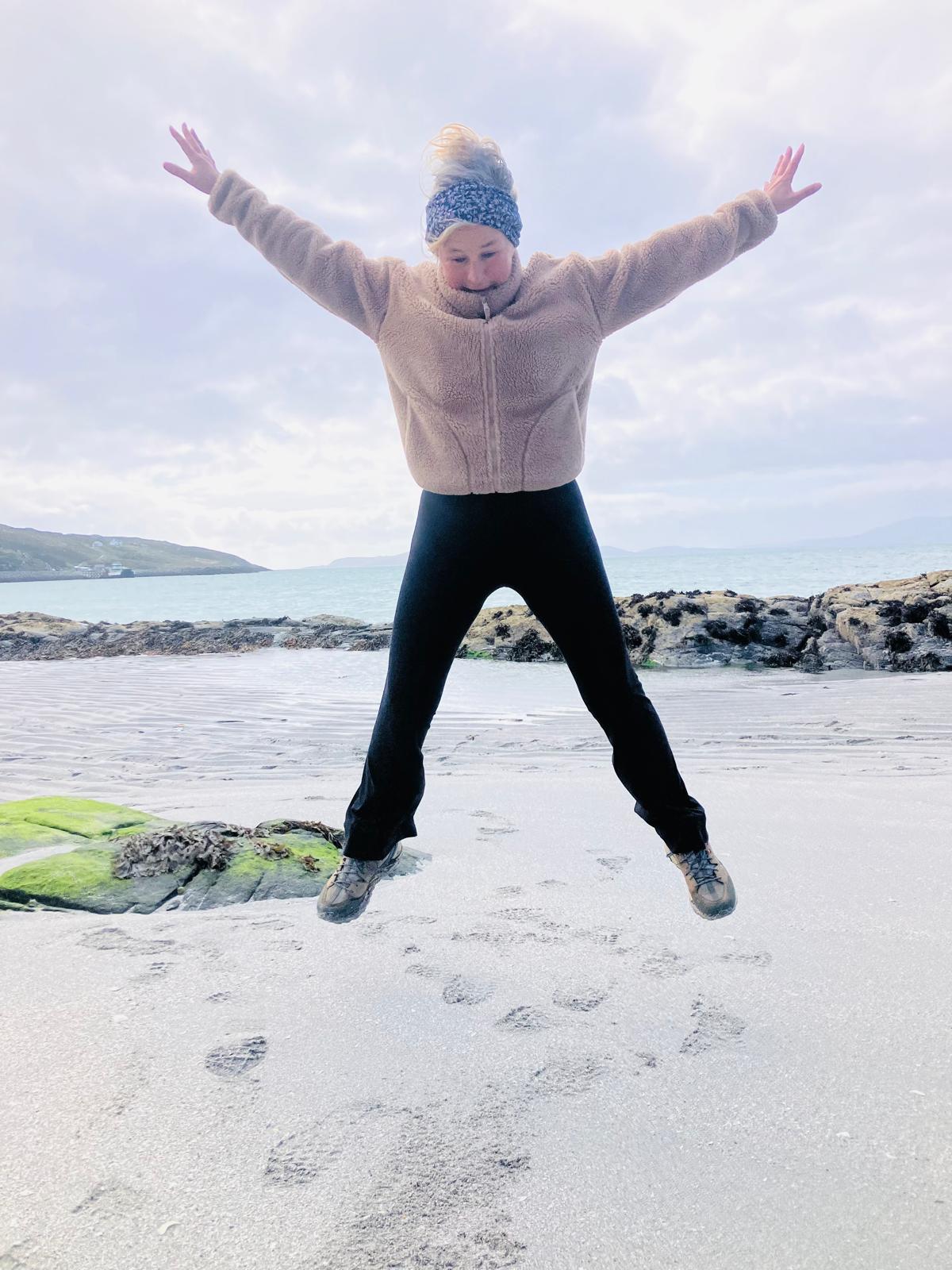 Gail jumping on a beach