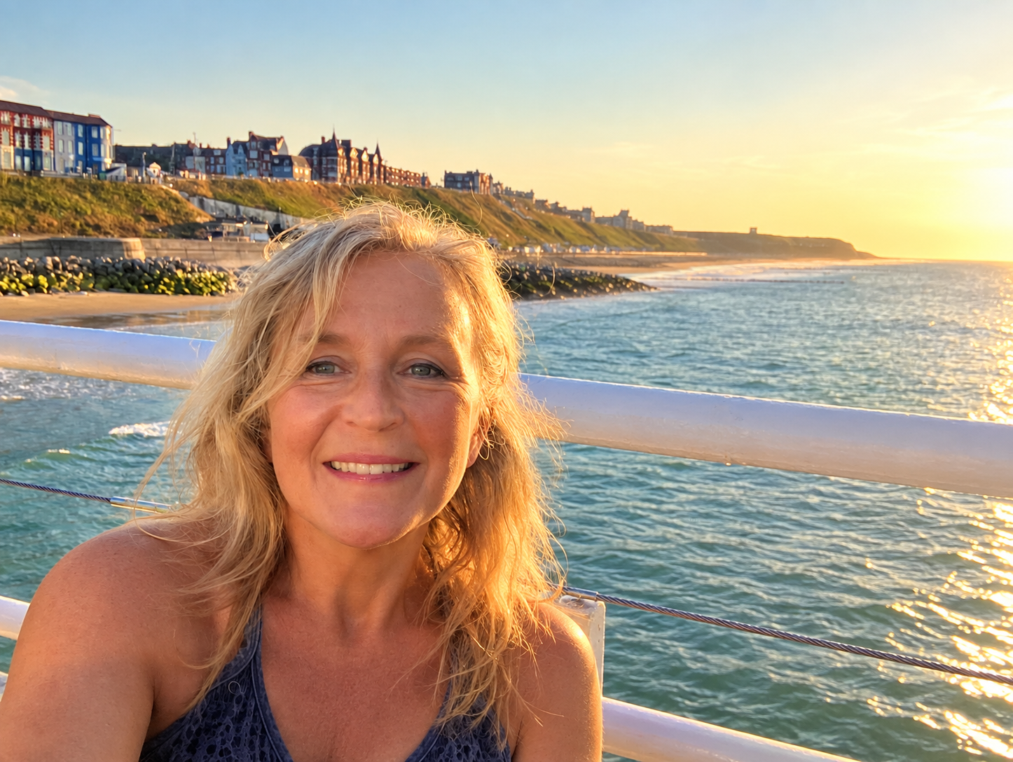 Gail smiling by the sea at sunset